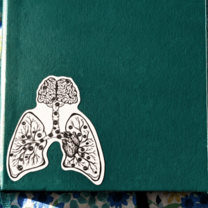 Vinyl sticker is shown affixed to a notebook for scale